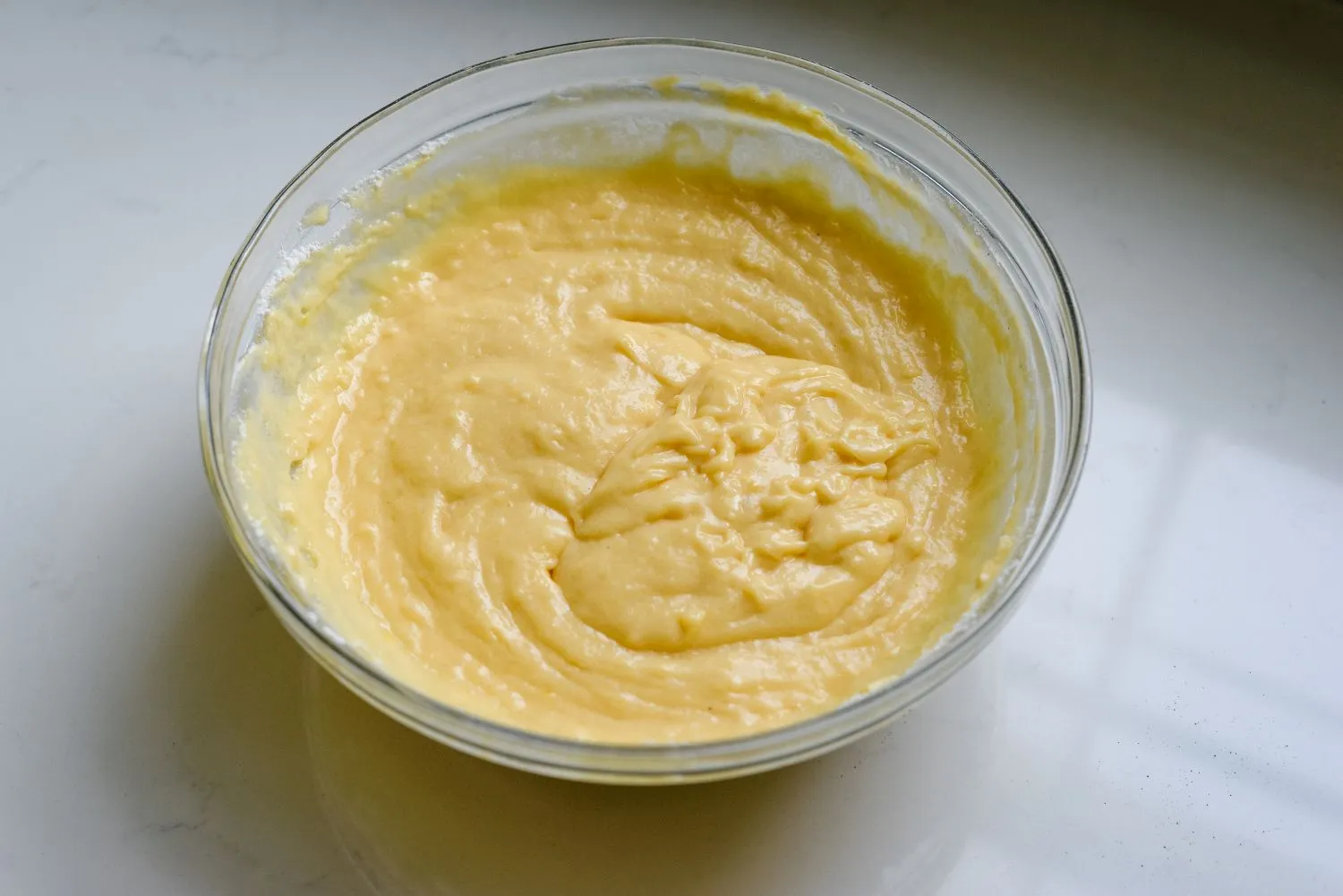 A large bowl filled with yogurt, melted butter, eggs, and vanilla extract whisked until smooth.