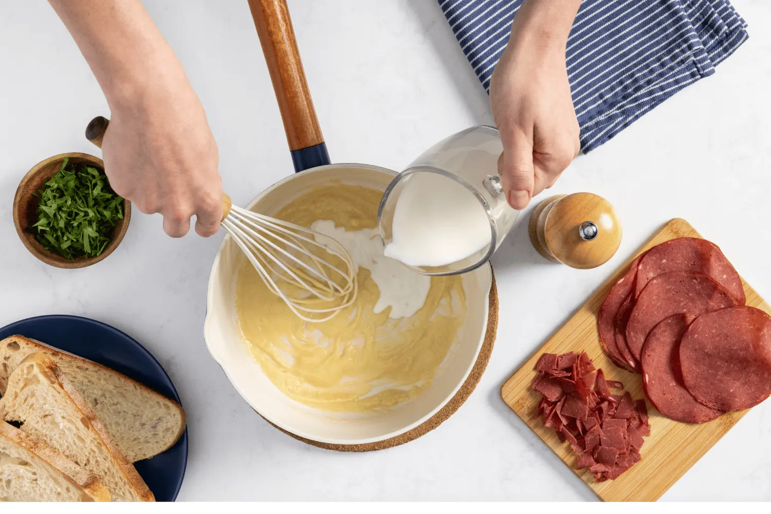 Melted butter in a small pot with milk and flour whisked on top.