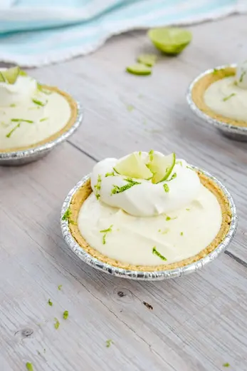 Mini-Key-Lime-Pies-4.jpg Three no-bake key lime pies topped with lime slices and whipped cream ready to serve.
