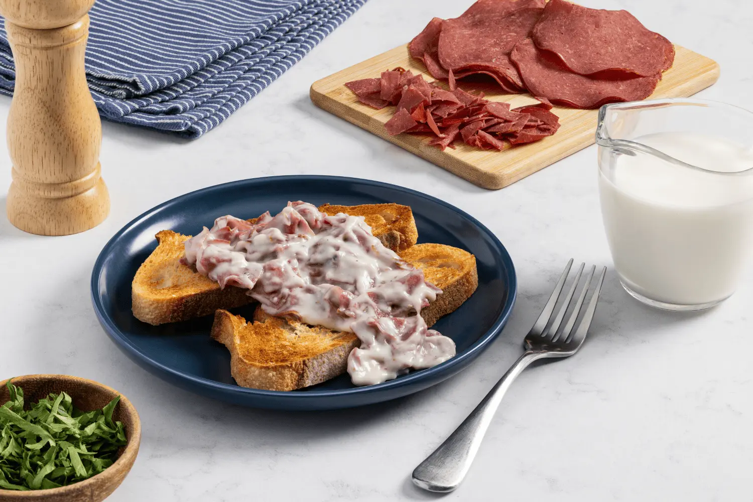 Chipped beef mixture on top of two slices of sourdough toast served on a plate.