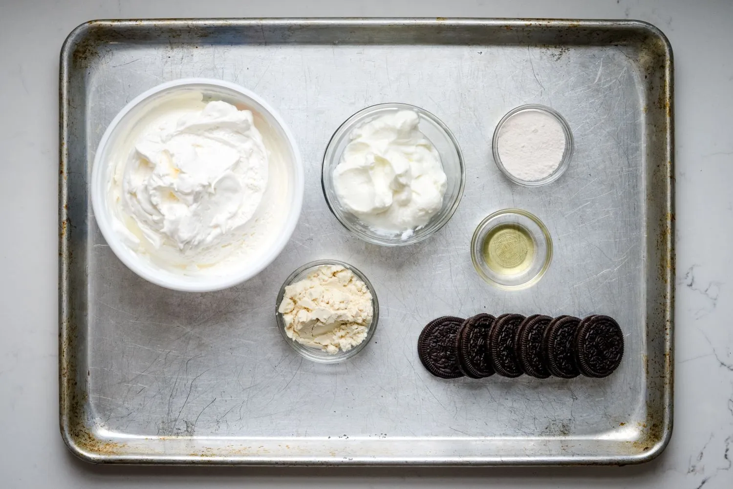 Ingredients for cookies and cream protein fluff yogurt including Greek yogurt, whey protein pwder, and pudding mix.
