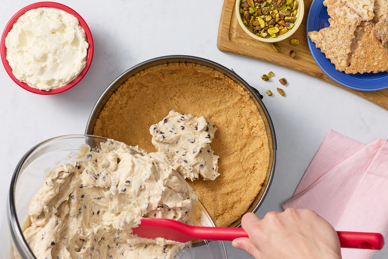 Spreading chocolate chip cheesecake filling into a graham cracker crust.