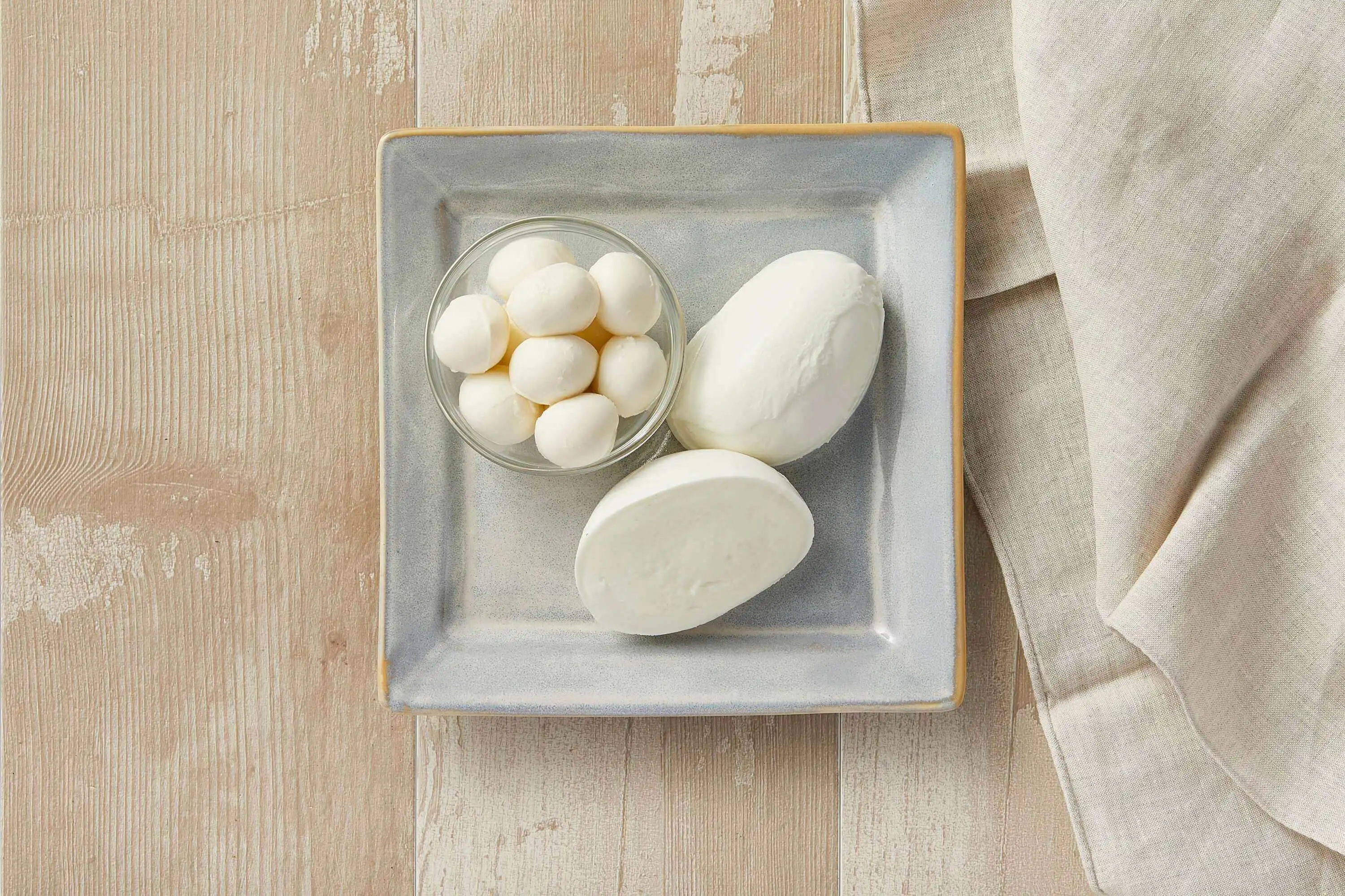 Simple and elegant presentation of fresh mozzarella cheese on a gray ceramic square plate.