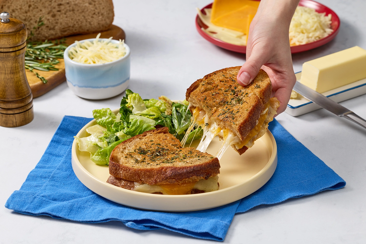 Finished recipe on a dish with salad and someone grabbing half to take a bite.