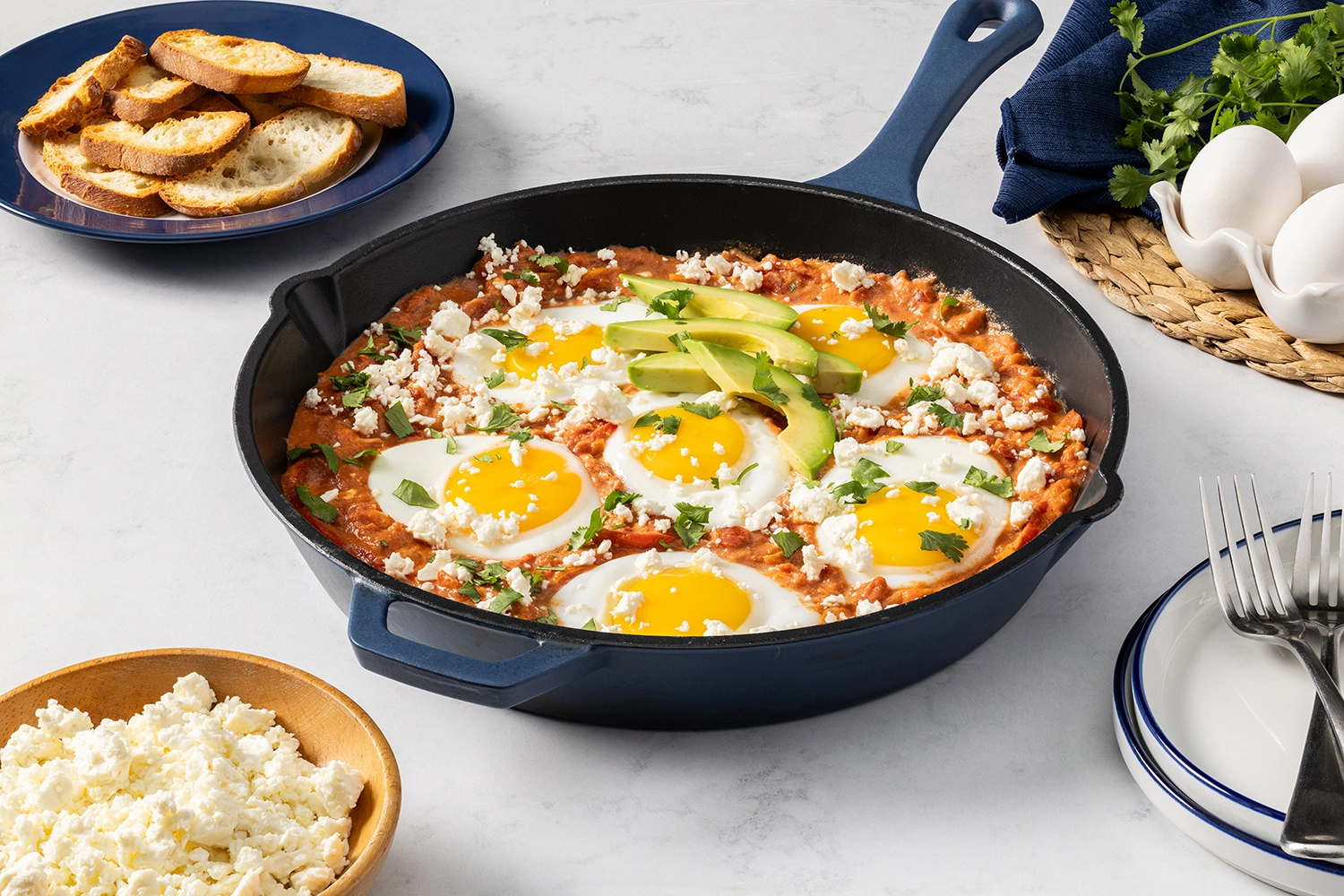 shakshuka eggs with feta cheese topped with avocado and chopped cilantro in a skilled served for breakfast.