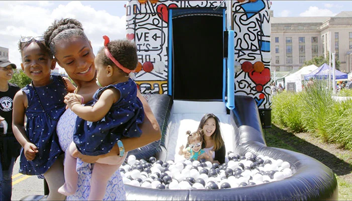 Olympian Dominique Dawes smiling while holding two kids.