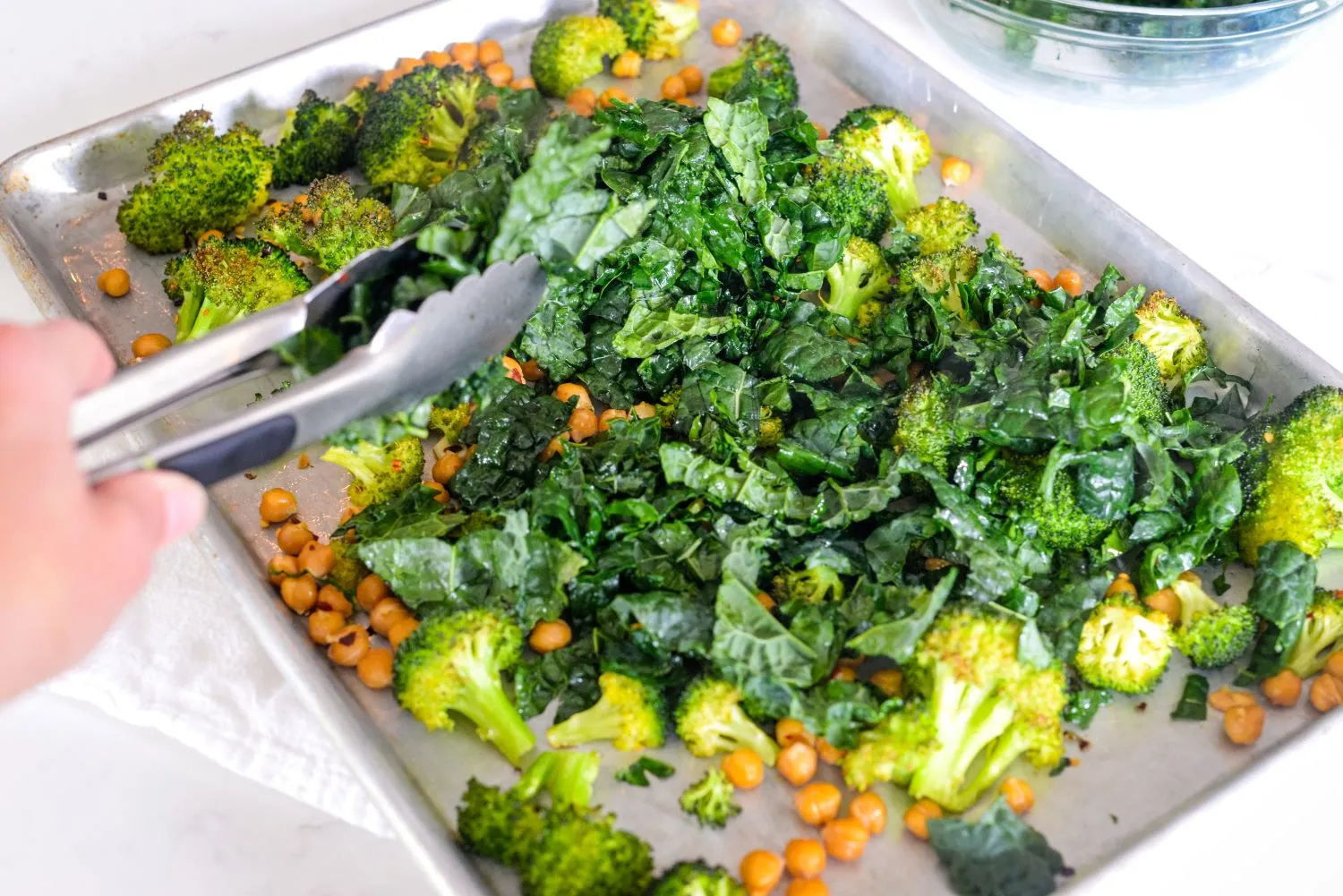 Broccoli, chickpeas, and kale mixture spread on a sheet pan
