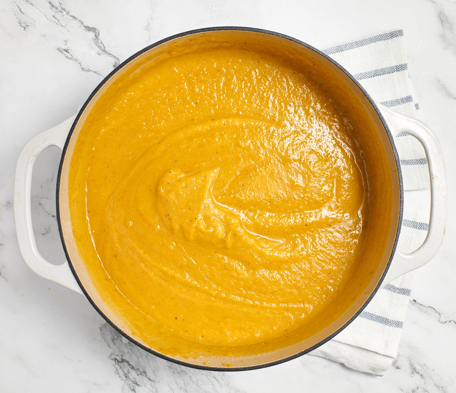 A bowl of roasted pumpkin pear soup after being pureed with an immersion blender.