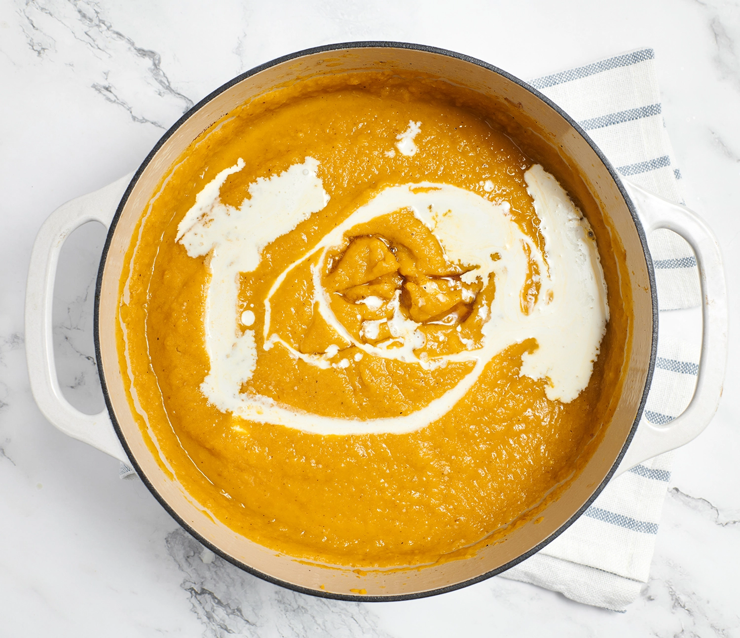 A bowl of roasted pumpkin pear soup topped with a swirl of Greek yogurt.