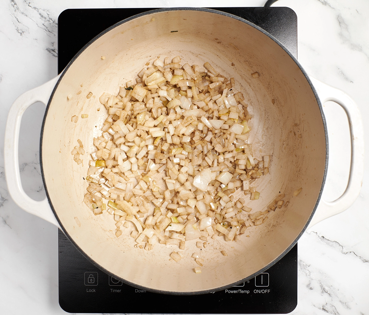 A bowl of chopped yellow onions and garlic cooked until softened.