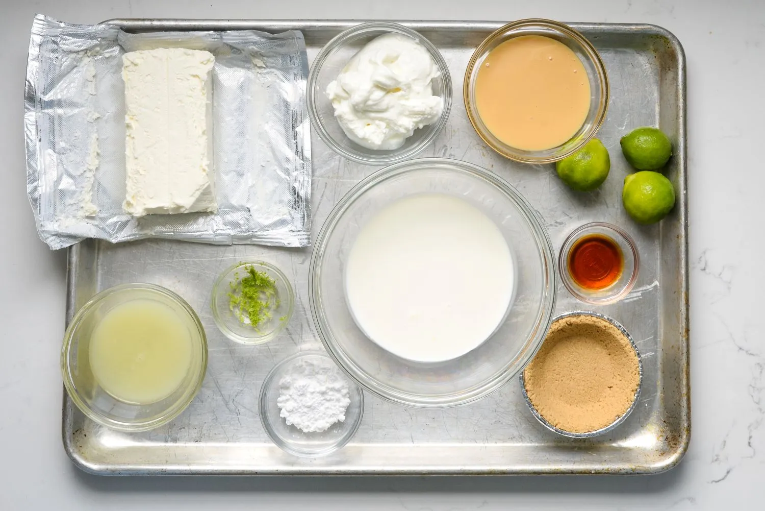 Mini-Key-Lime-Pies-(1).jpg Ingredients for no-bake mini key lime pies including cream cheese, Greek yogurt, key lime juice, graham cracker pie crusts, sweetened condensed milk, whipping cream, powdered sugar, and vanilla extract.