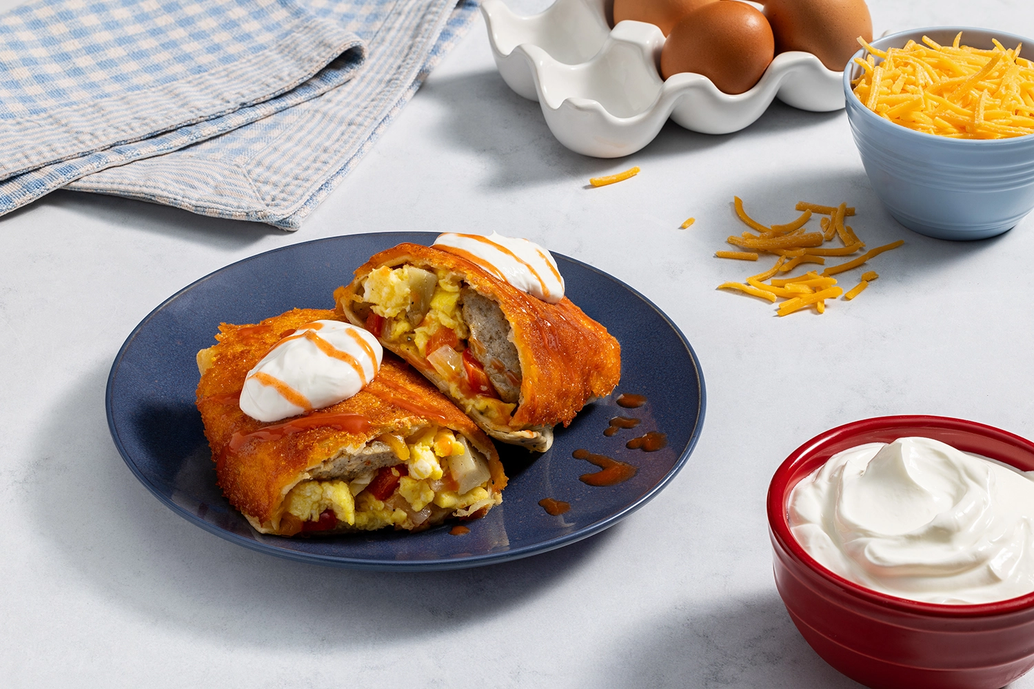 A grilled cheese breakfast burrito cut in half on a blue plate