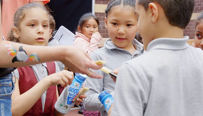 Group of happy kids enjoying milk and cheese in school.