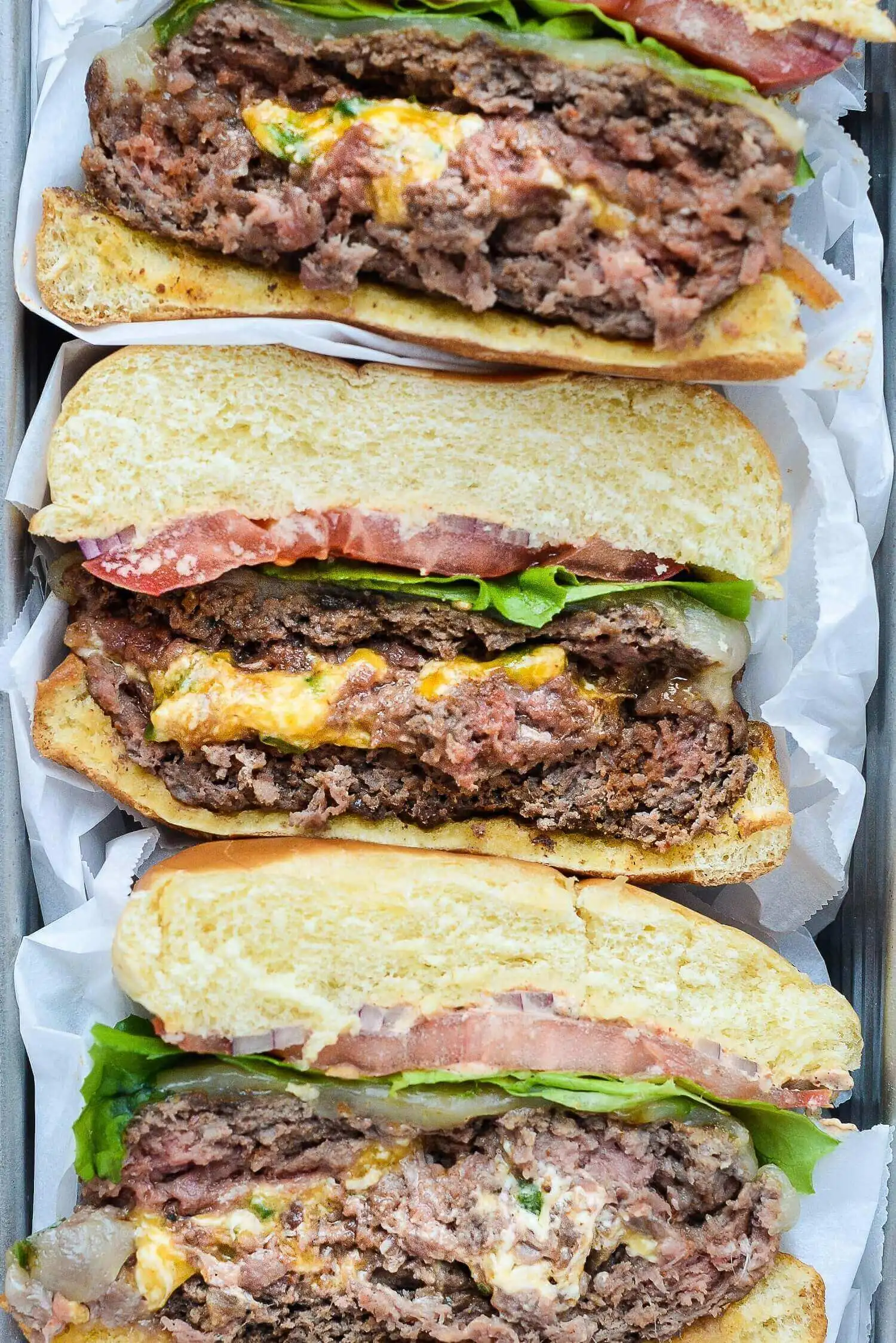 Aerial view of Jalapeño Popper Burgers split and served on a plate wrapped in white paper.