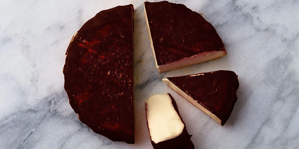 A wheel of cheese with a rind covered in different things to provide additional flavor.