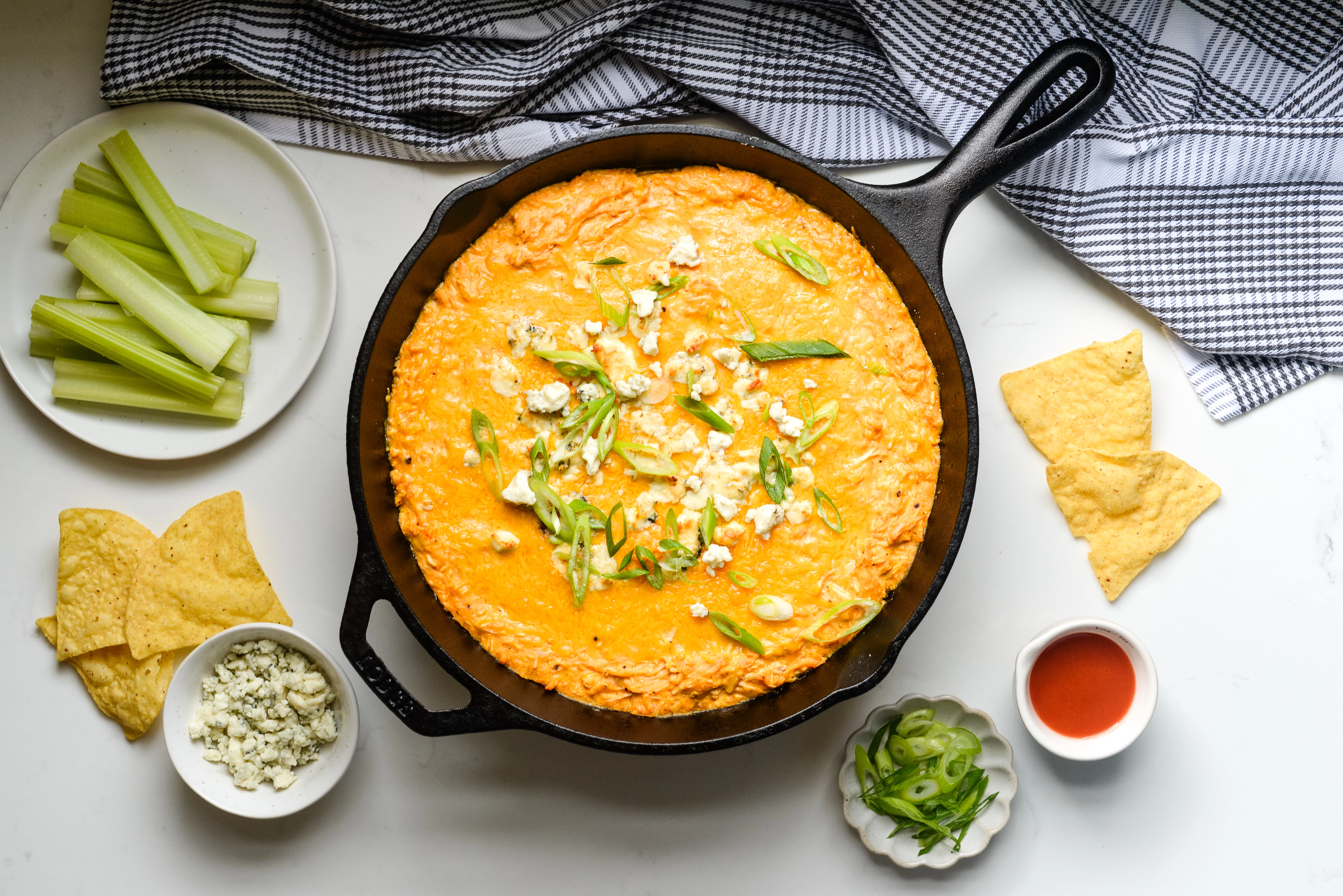 Cottage cheese buffalo chicken dip in a skillet topped with cheddar cheese and blue cheese crumbles