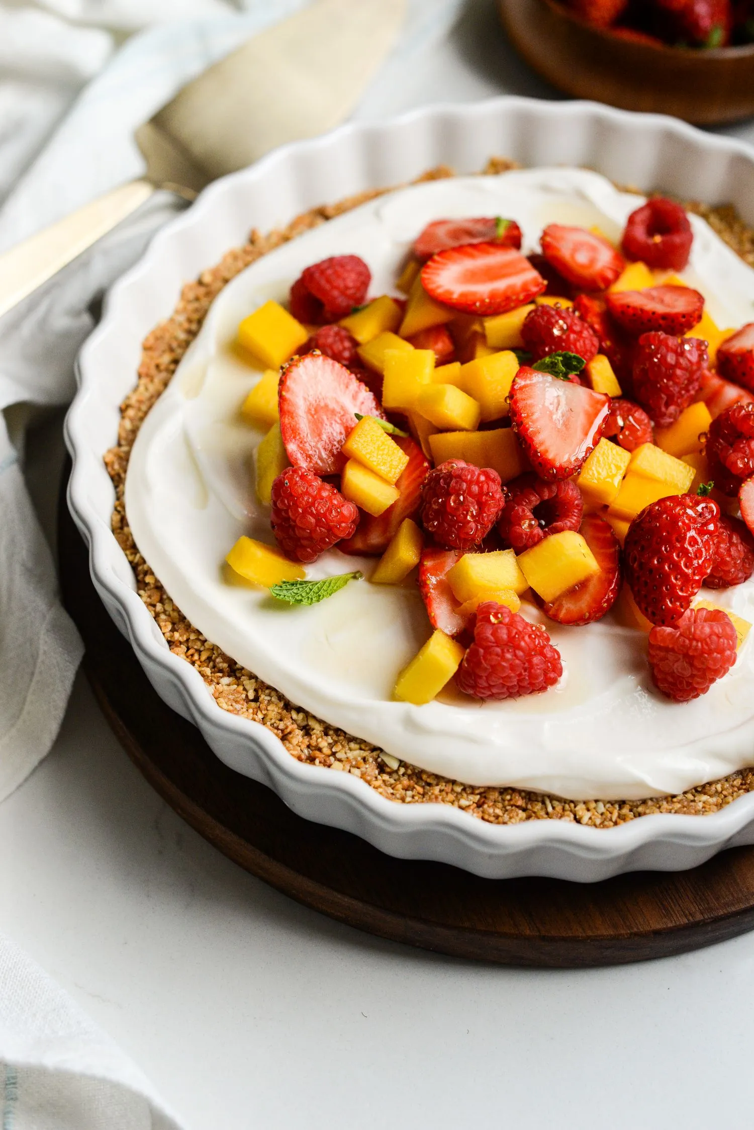 No-bake Greek yogurt fruit tart topped with a drizzle of honey and fresh mint.