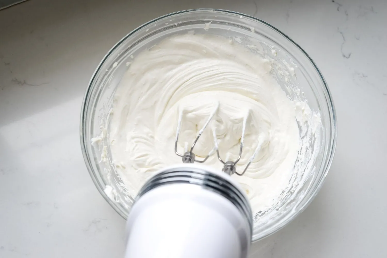 Greek yogurt, protein powder and pudding mix in a large bowl being beat with a hand mixer