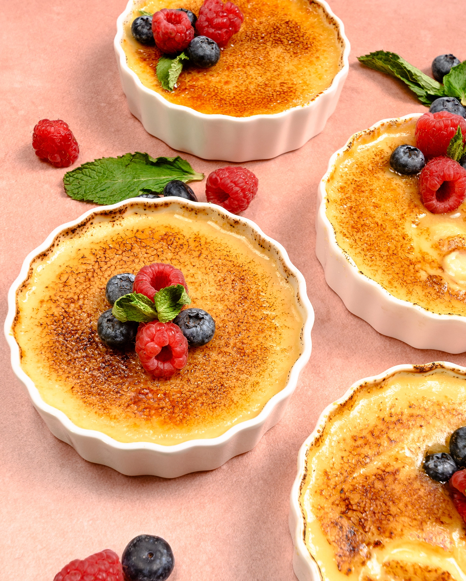 High Protein Greek Yogurt Crème Brulee served in a ramekin and topped with raspberries and blueberries.