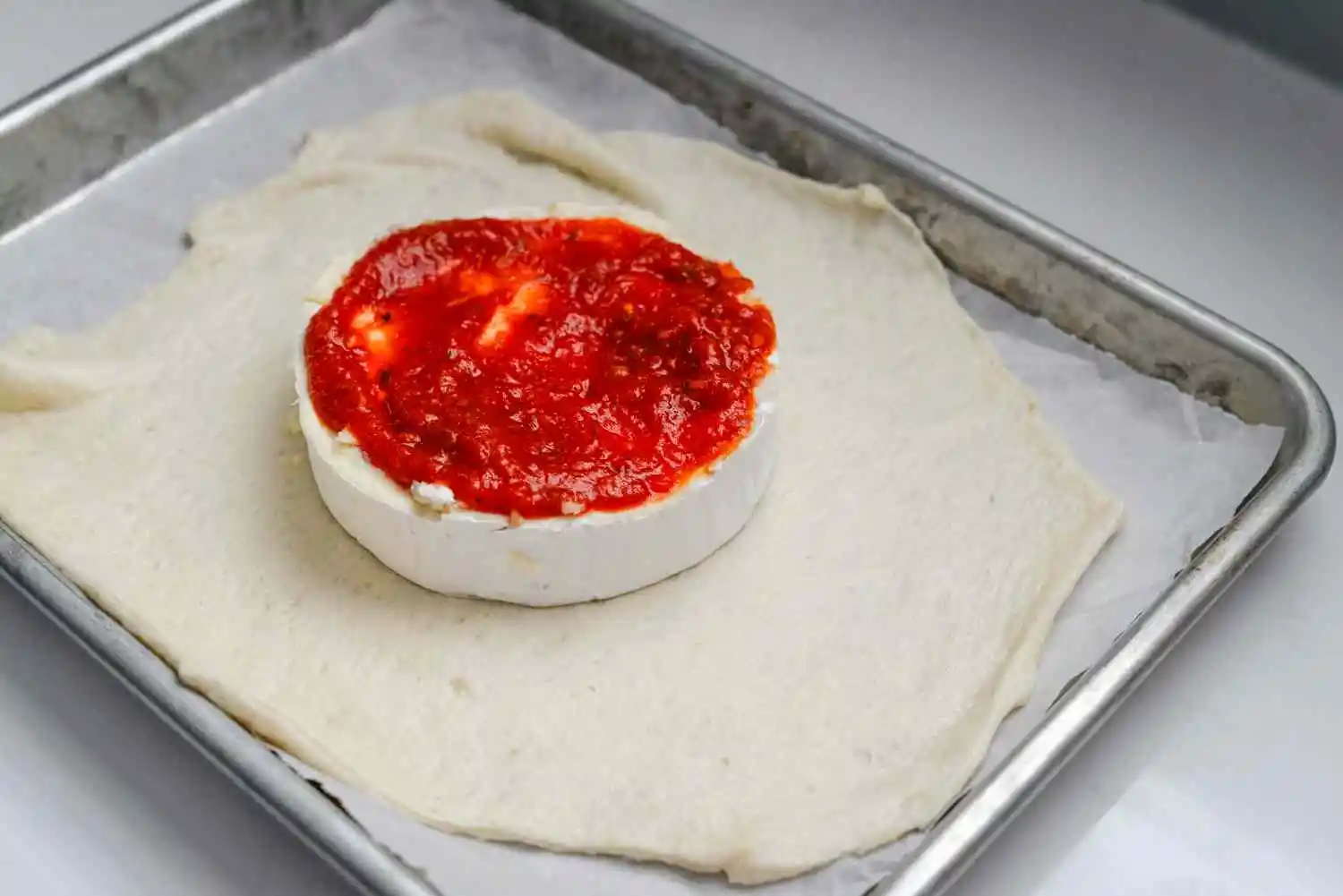 Brie wheel with garlic and pizza sauce with mozzarella and peperoni on top of pizza crust