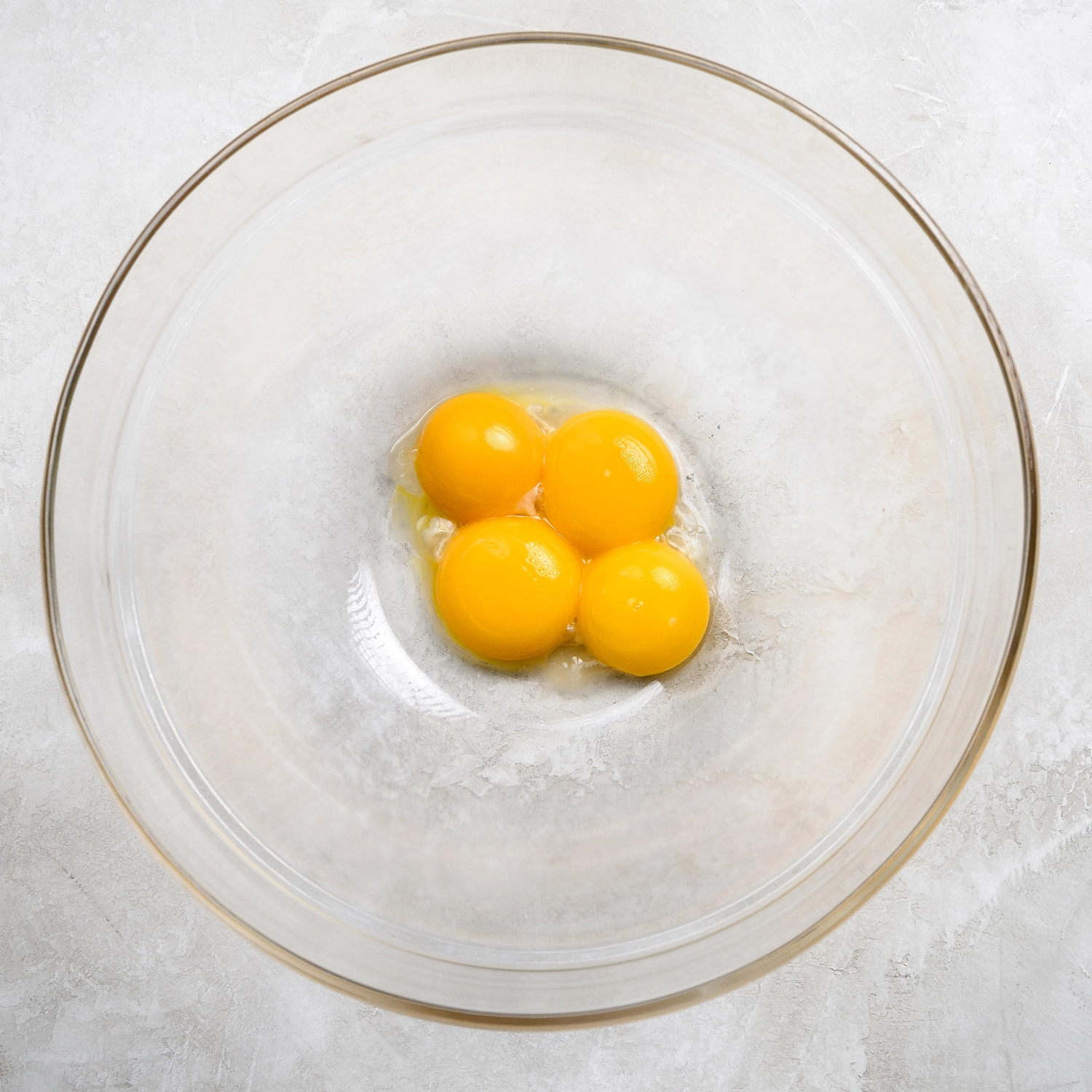 Four egg yolks separated in a bowl.
