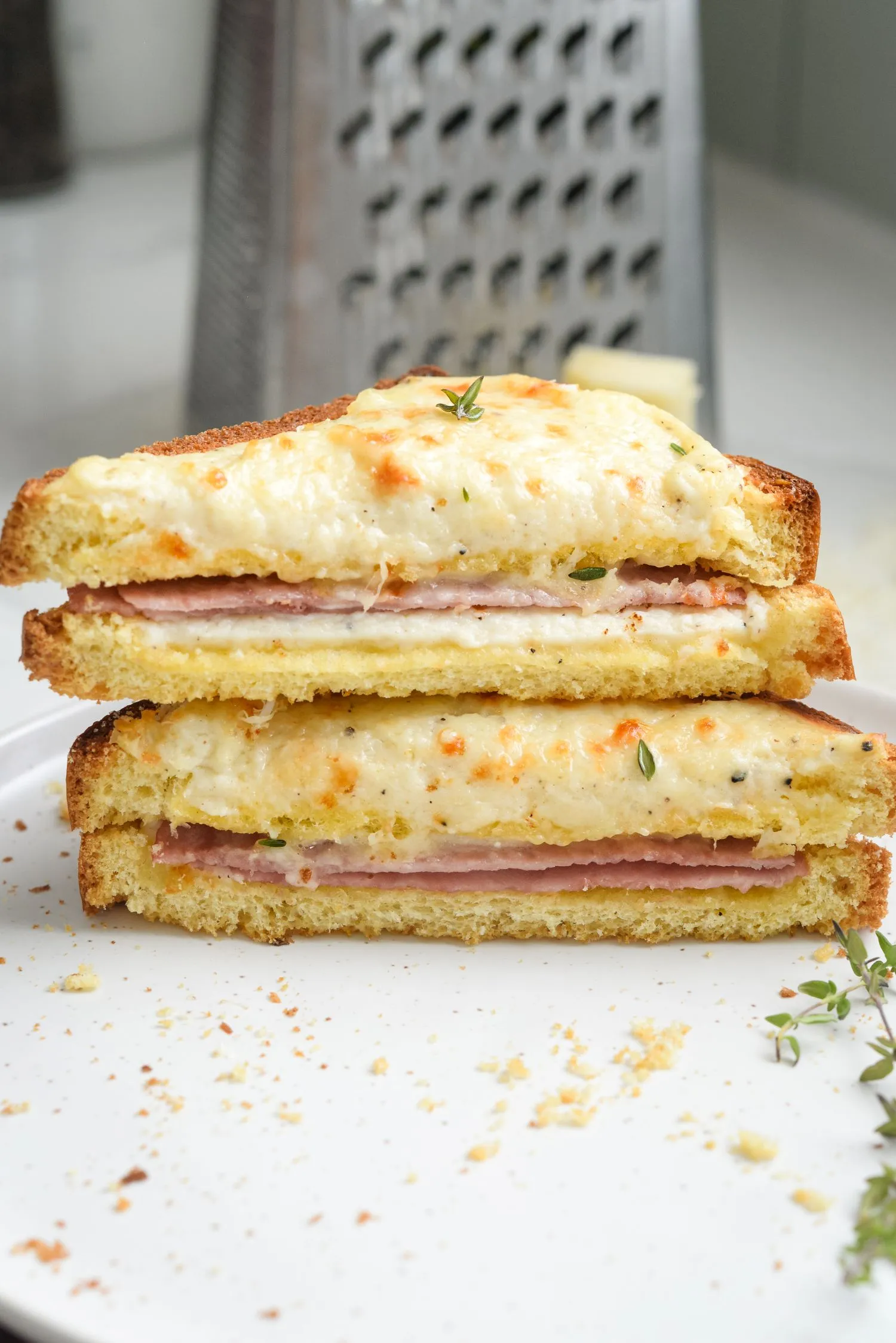 Sliced baked Croque Monsieur sandwiches garnished with thyme, plated to serve.