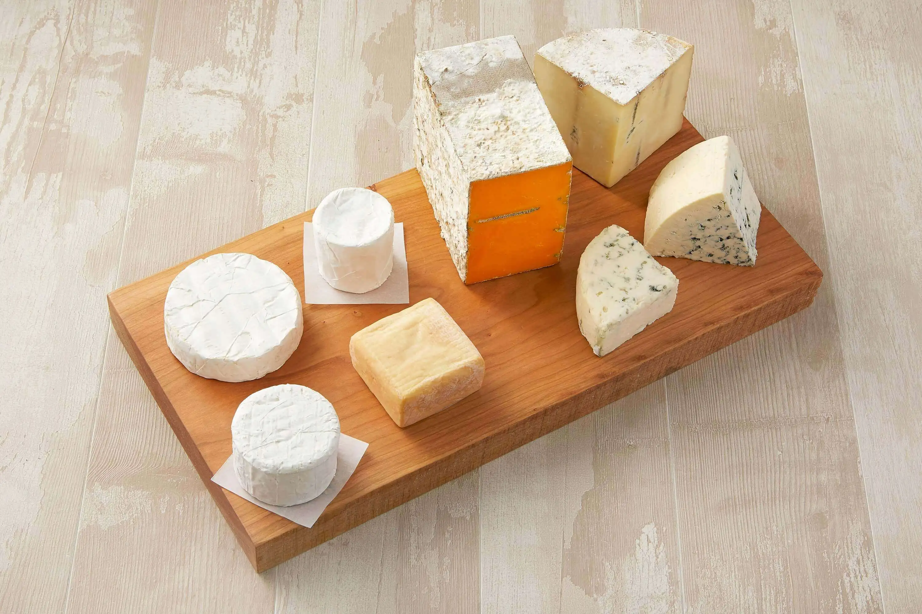 A delightful cheese platter on a wooden table, offering an assortment of cheeses, including types of brie and blue cheese.