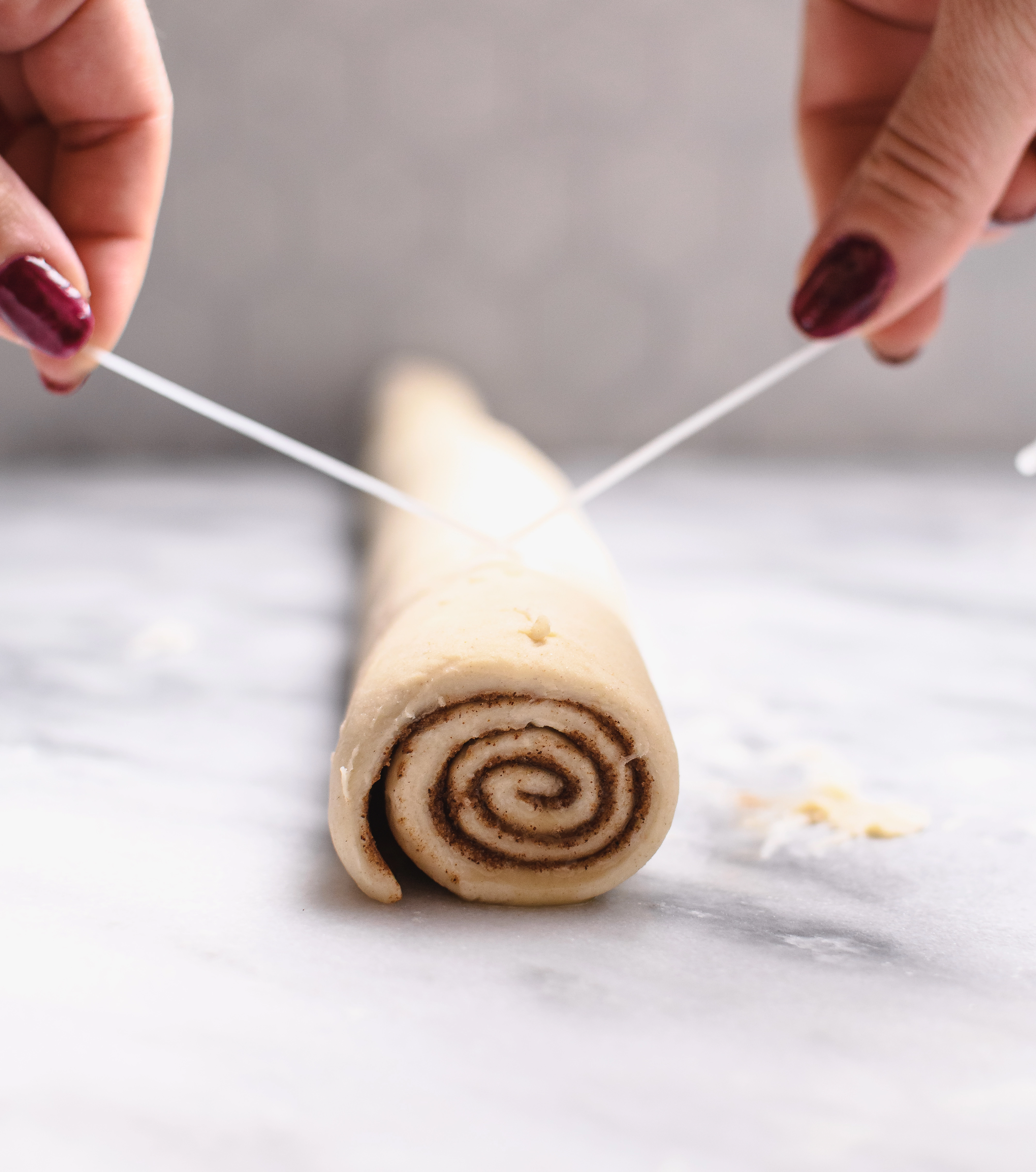 Greek Yogurt Chai Cinnamon Roll dough rolled into a log to be cut into rolls using floss.